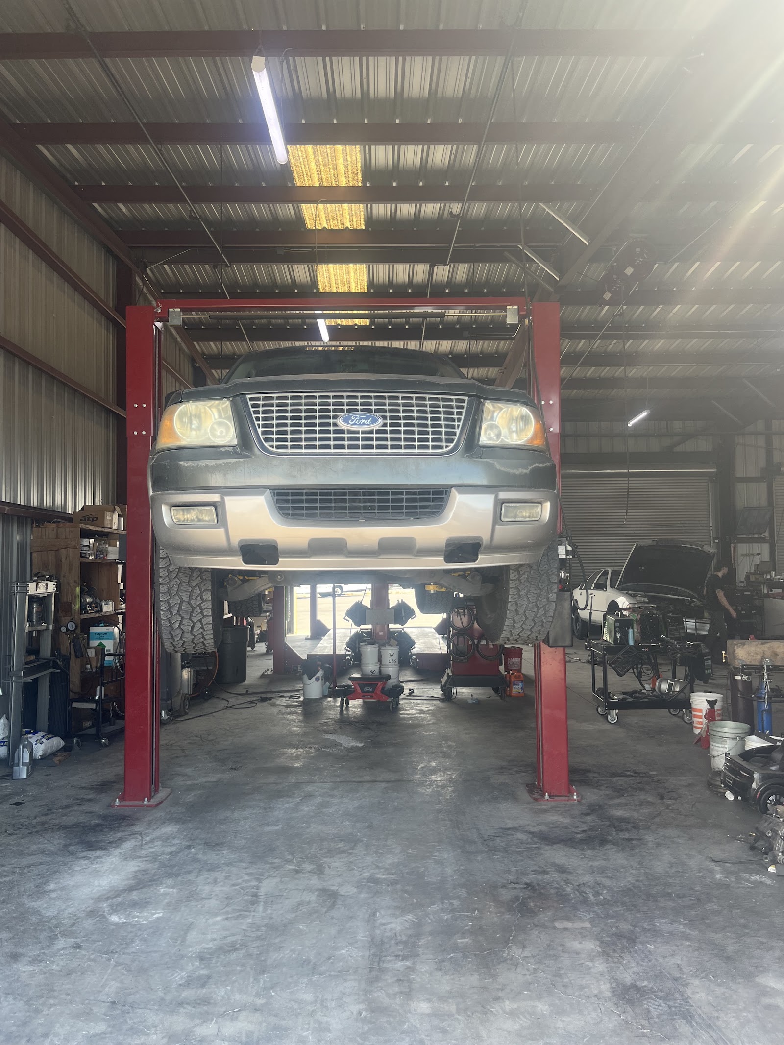 Ford Expedition on a four-post lift inside a repair shop bay