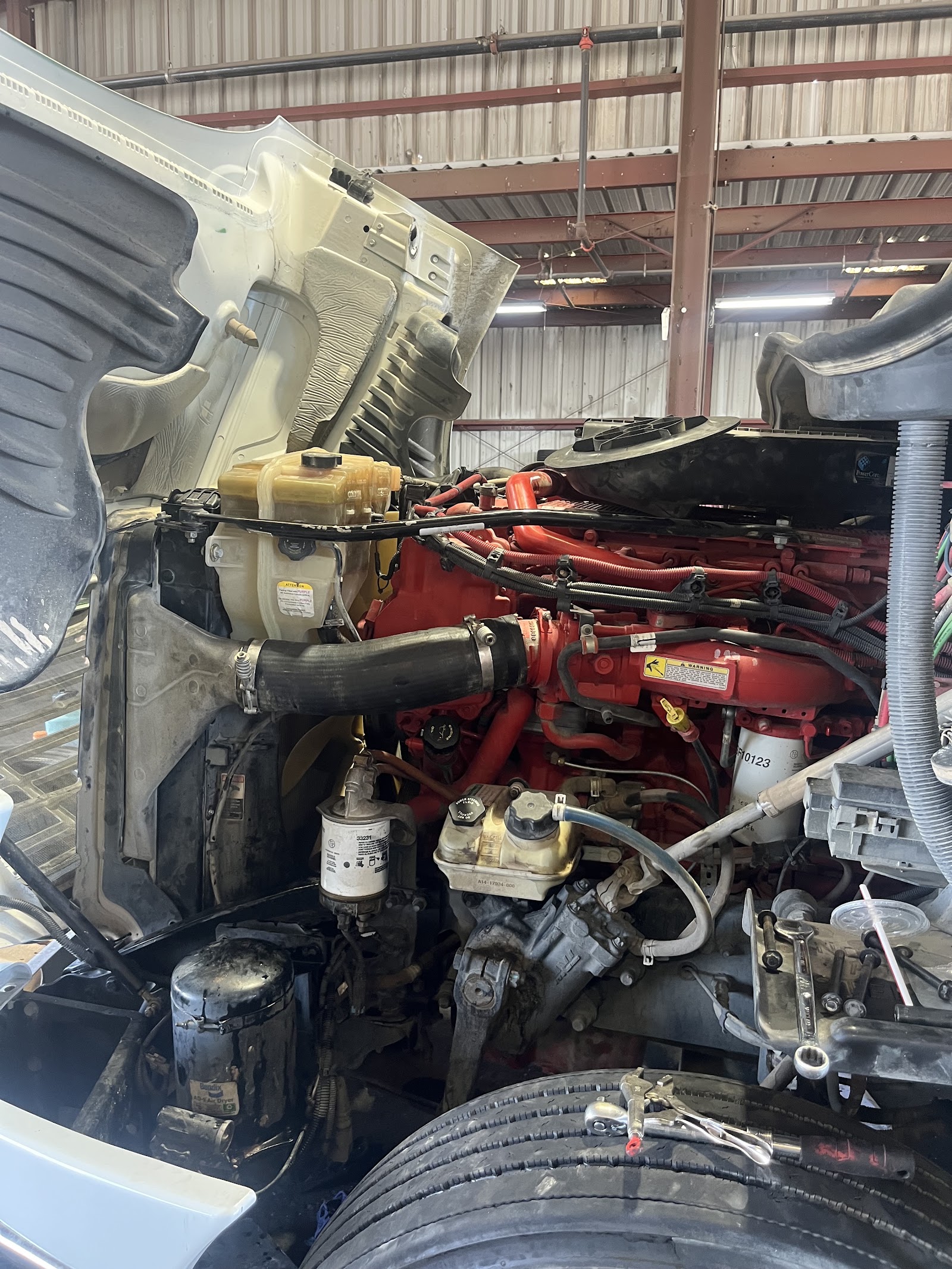 Semi-truck engine bay open showing red diesel engine during repair